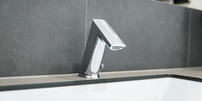 Ein moderner Wasserhahn aus glänzendem Metall, der elegant über einer weißen Badewanne positioniert ist.