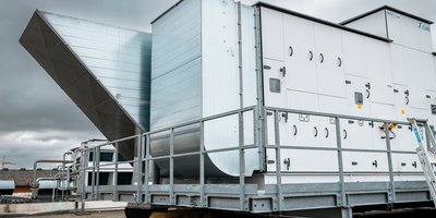Eine große, moderne Maschinenanlage mit einem schrägen Metallauslass steht vor einem bewölkten Himmel.