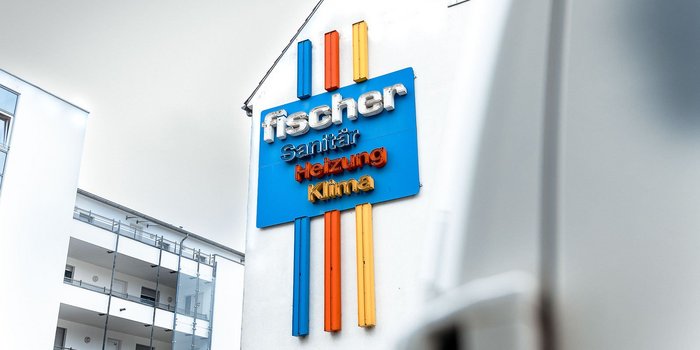 Das auffällige Schild von Fischer zeigt Dienstleistungen in Sanitär, Heizung und Klima in leuchtenden Farben.