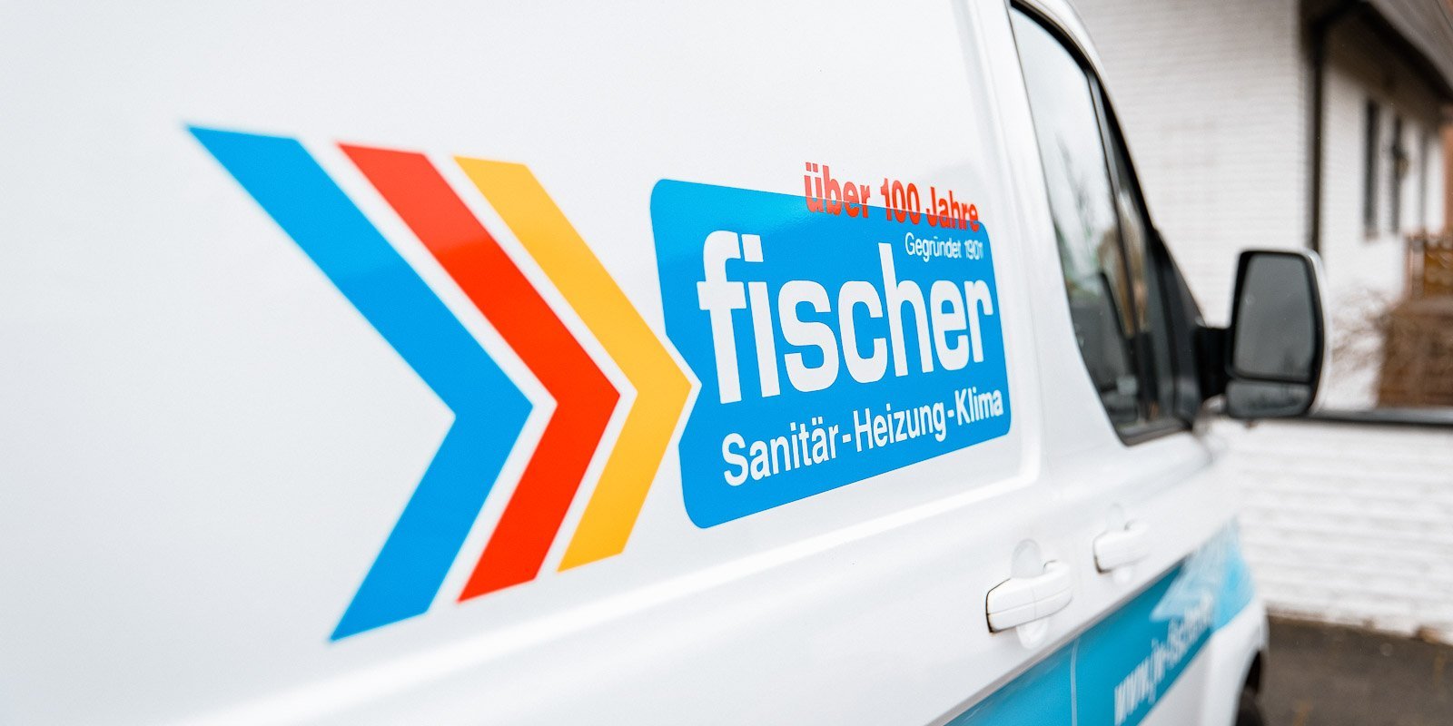 Das Fahrzeug trägt das Logo von Fischer, einem Unternehmen für Sanitär, Heizung und Klima, mit auffälligen Farben.