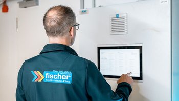 Der Mann mit Brille und Glatze steht vor einem Kühlschrank und überprüft die Einstellungen auf einem Bildschirm.